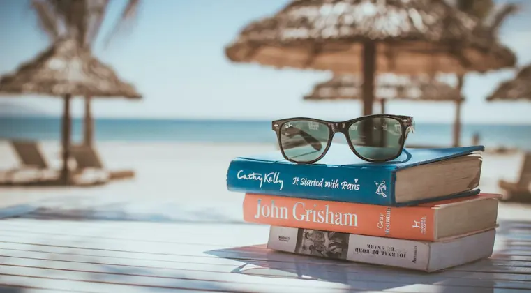 A picture of 3 books on a table on a beach
